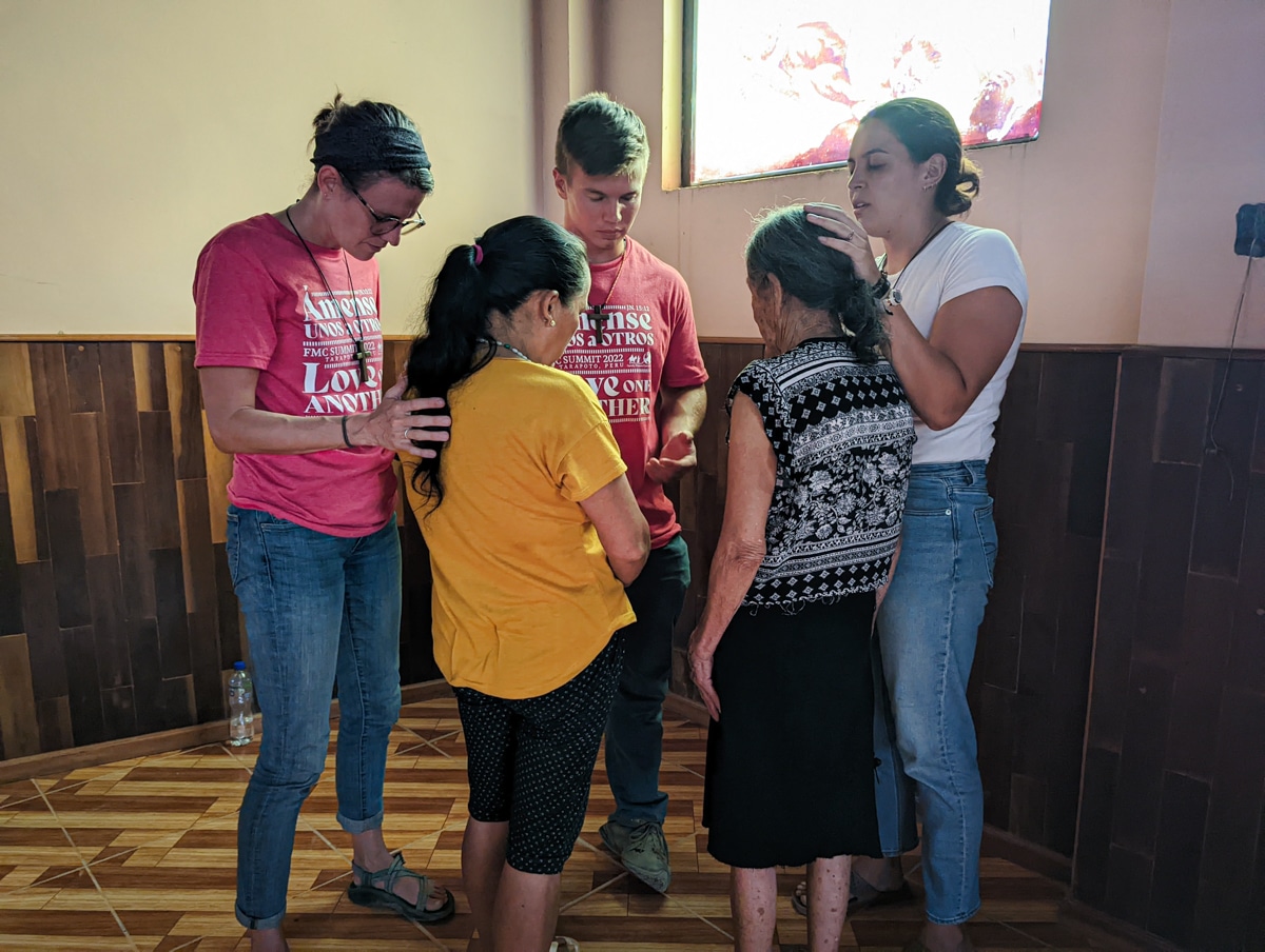 Missionaries praying over women in Peru